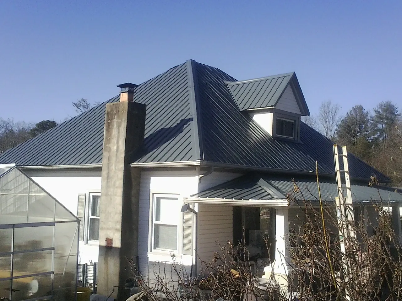 Dark blue standing seam metal roof on a white farmhouse with dormer — Slate & Tile Roof Repair by Roofing Brothers in Plumtree