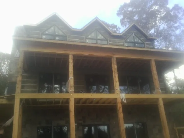 Dormers and porch framing on a large log home under construction — Roof Coating work by our crew in Plumtree