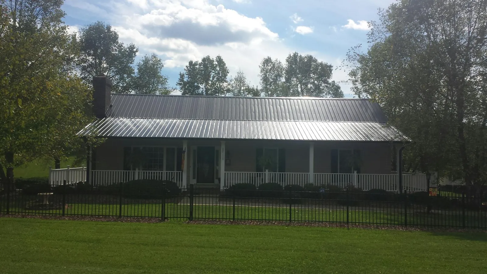 Gray metal roof on a brick ranch with a full width front porch — Gutter Guard Installation work by our crew in Plumtree