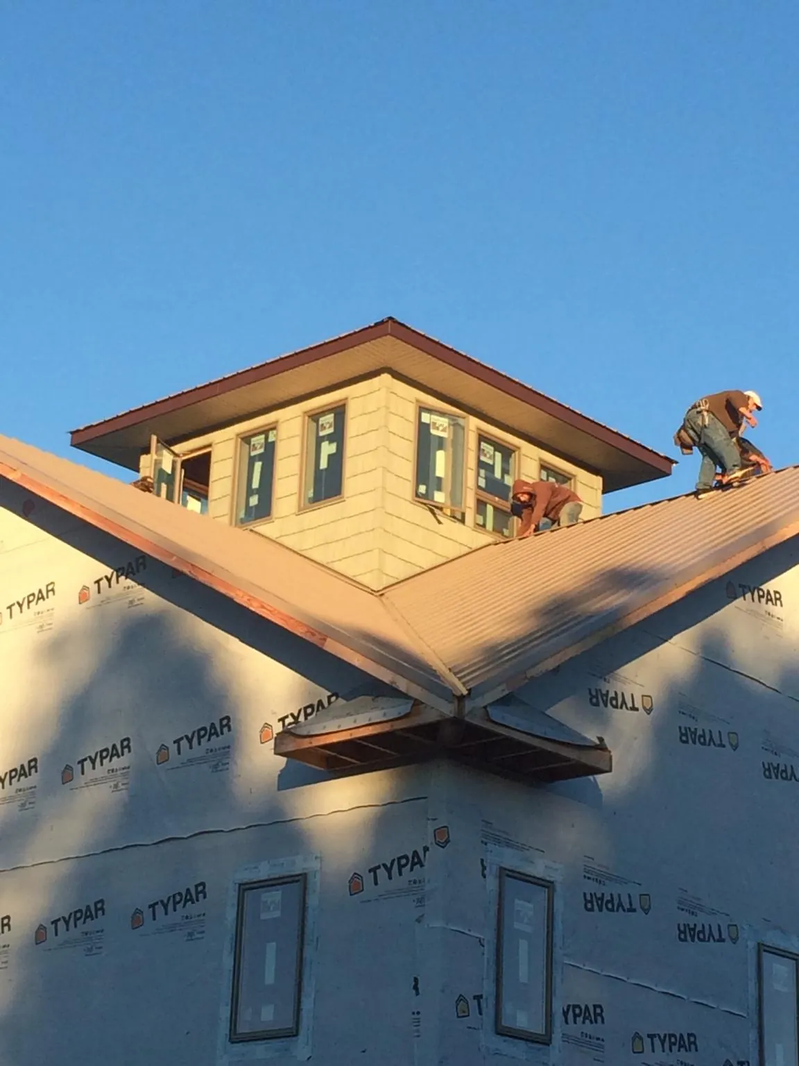 Roofers working around a rooftop cupola on a new metal roof at sunset — Roof Waterproofing in Plumtree by Roofing Brothers